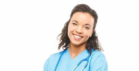 A healthcare professional wearing light blue scrubs with a stethoscope draped around the neck, standing with arms crossed against a plain white background.