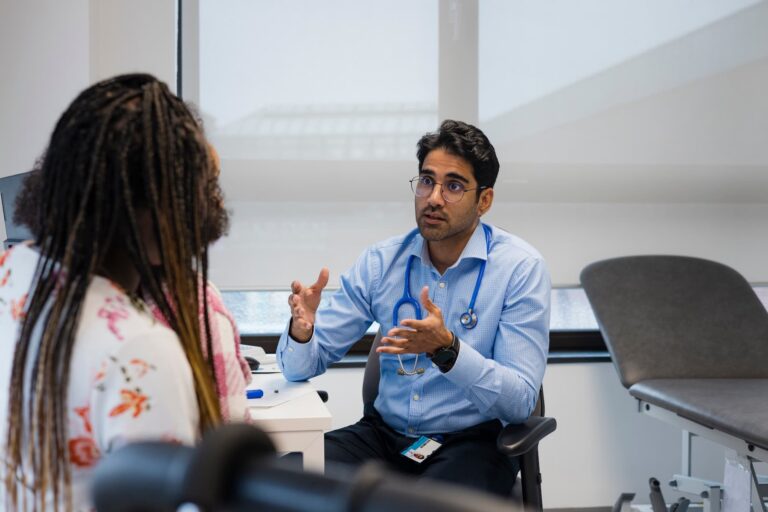 Healthcare professional speaking with a patient during a consultation in a medical office setting.