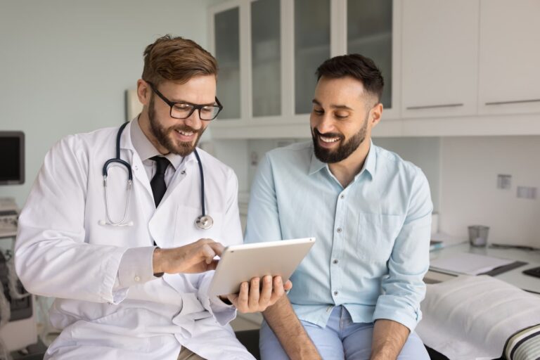 Healthcare professional reviewing information on a tablet with an adult patient during a medical appointment.