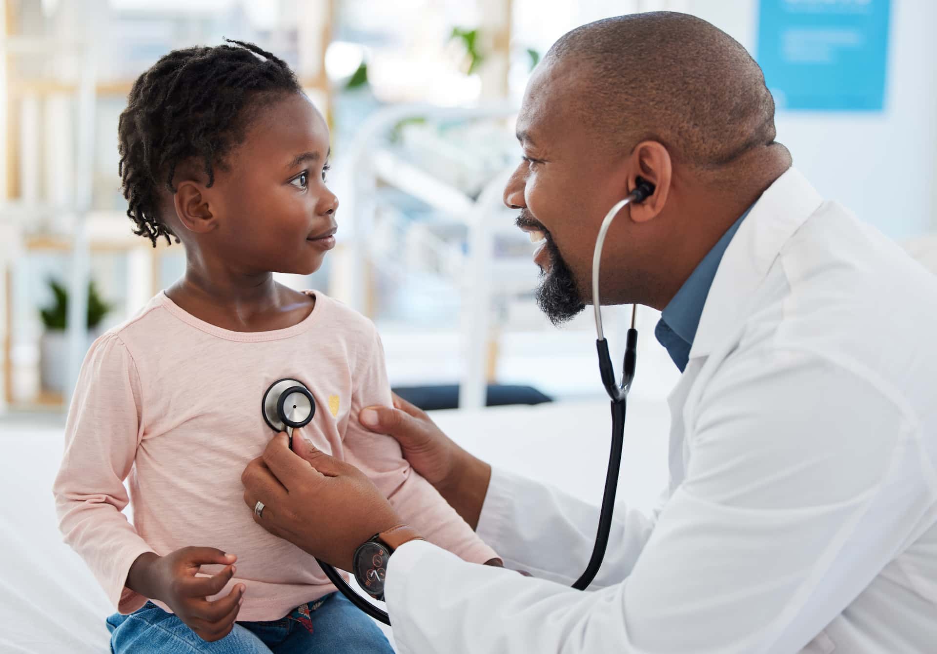 A healthcare professional using a stethoscope on a child in a medical setting.